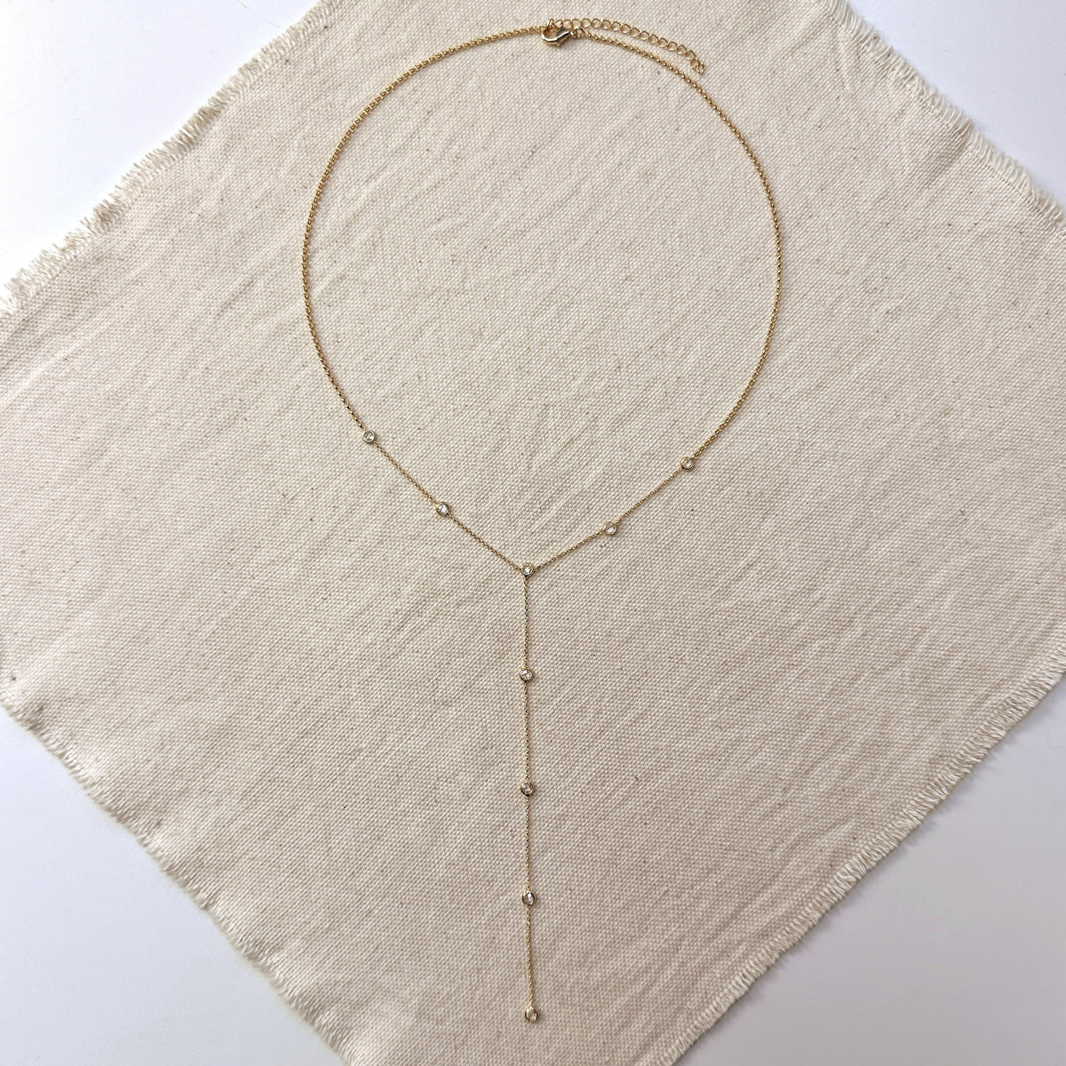 18k gold-filled lariat necklace with a single bezel-set CZ stone, a flattering wedding guest necklace for a V-neck dress