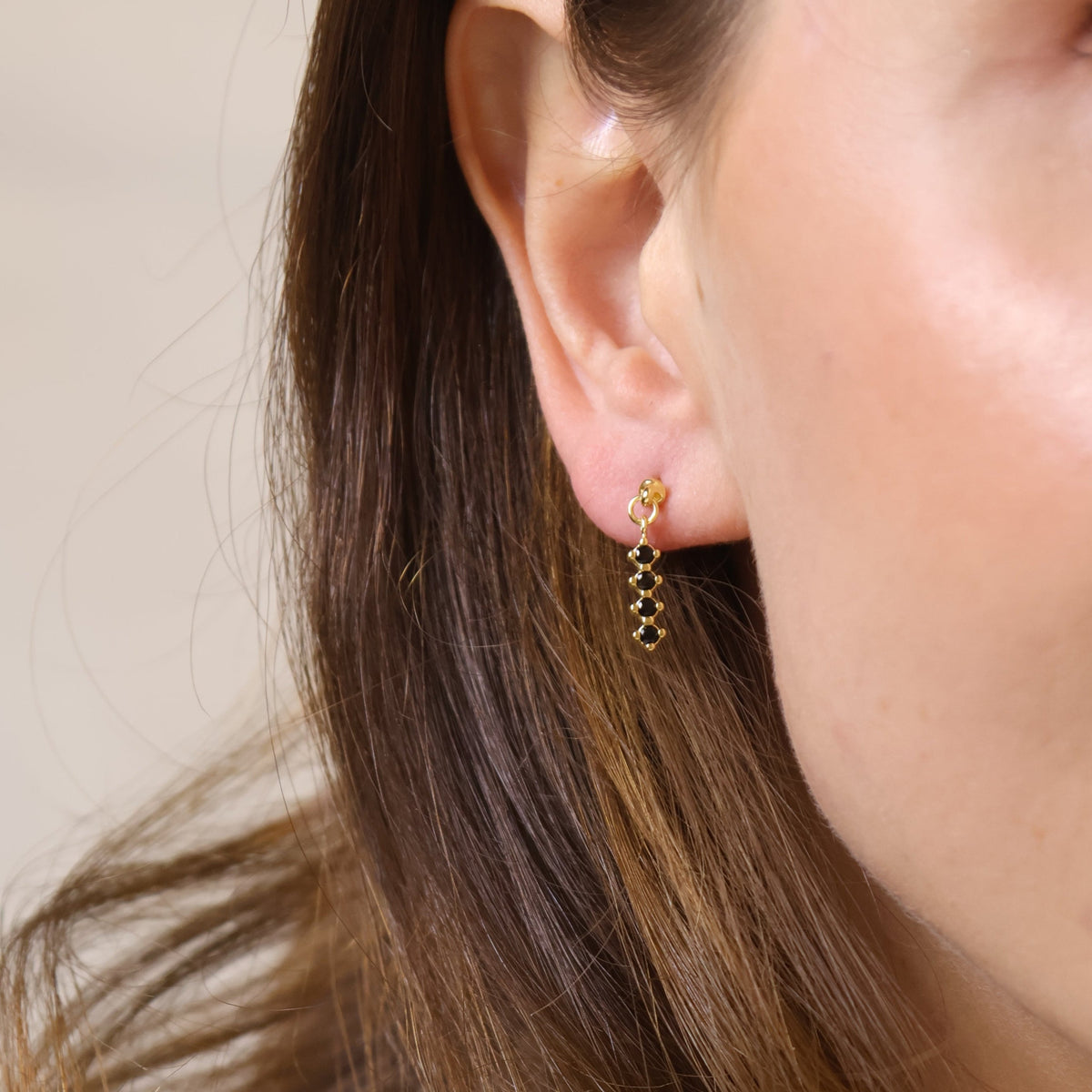 Close-up of a person wearing a gold earring with a neutral background