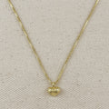 Gold necklace with a heart-shaped pendant on a beige fabric background
