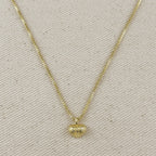 Gold necklace with a heart-shaped pendant on a beige fabric background