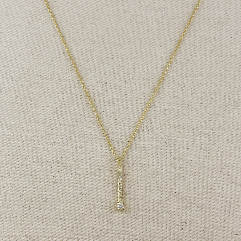 Gold necklace with a small diamond pendant on a beige fabric background