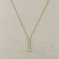 Gold necklace with a small diamond pendant on a beige fabric background