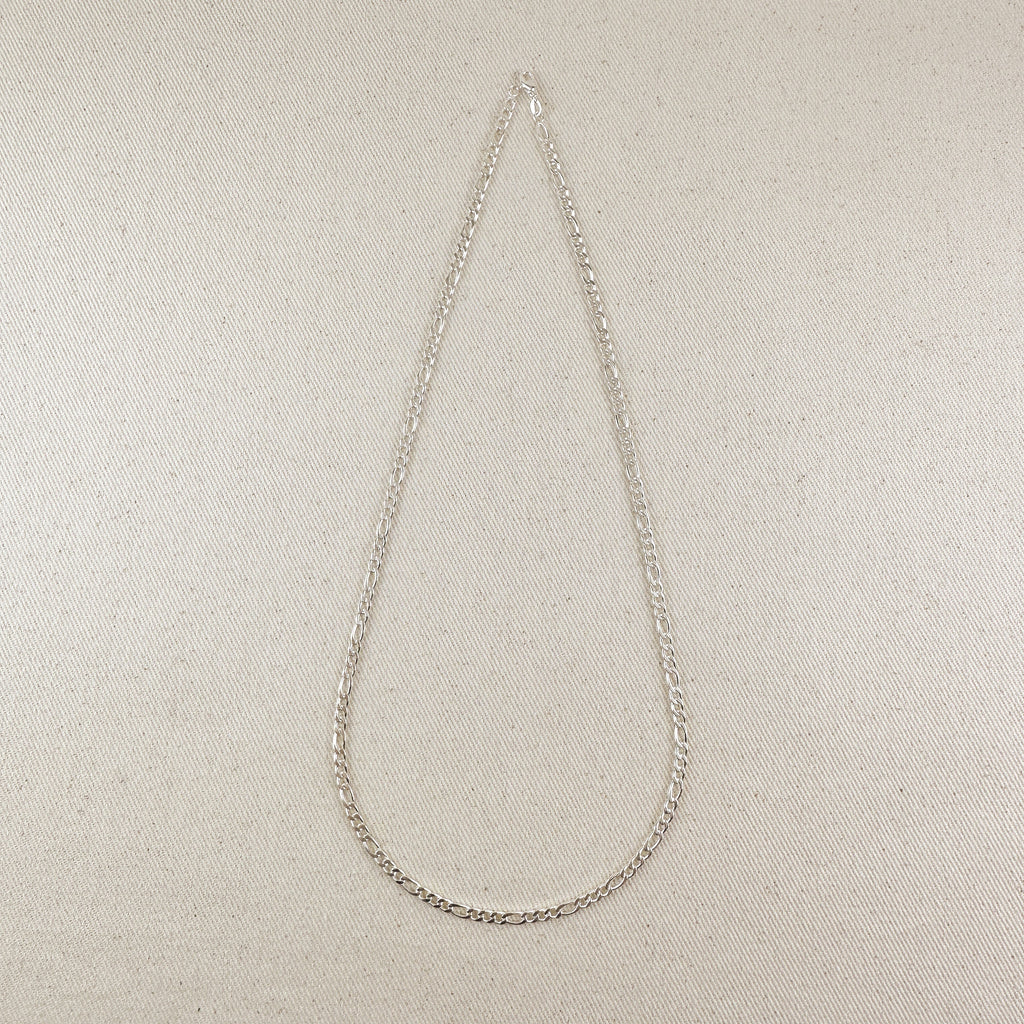 Silver chain necklace on a beige fabric background