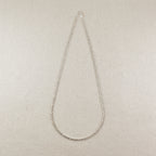 Silver chain necklace on a beige fabric background