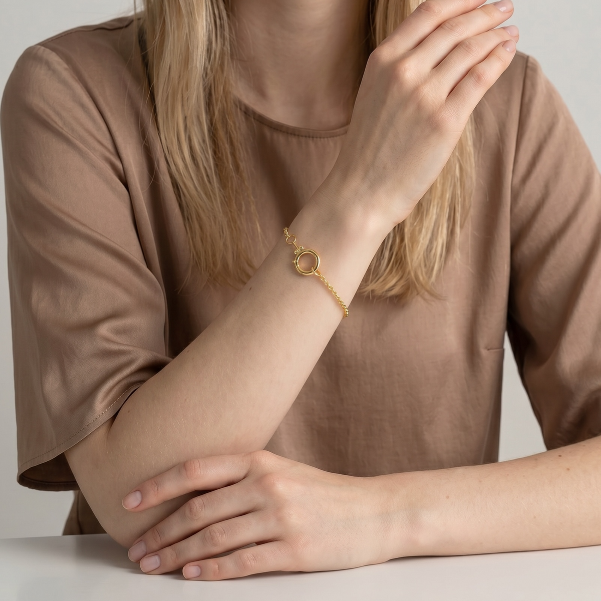 Woman wearing a gold bracelet on a plain background