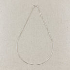 Silver necklace on a light gray textured background