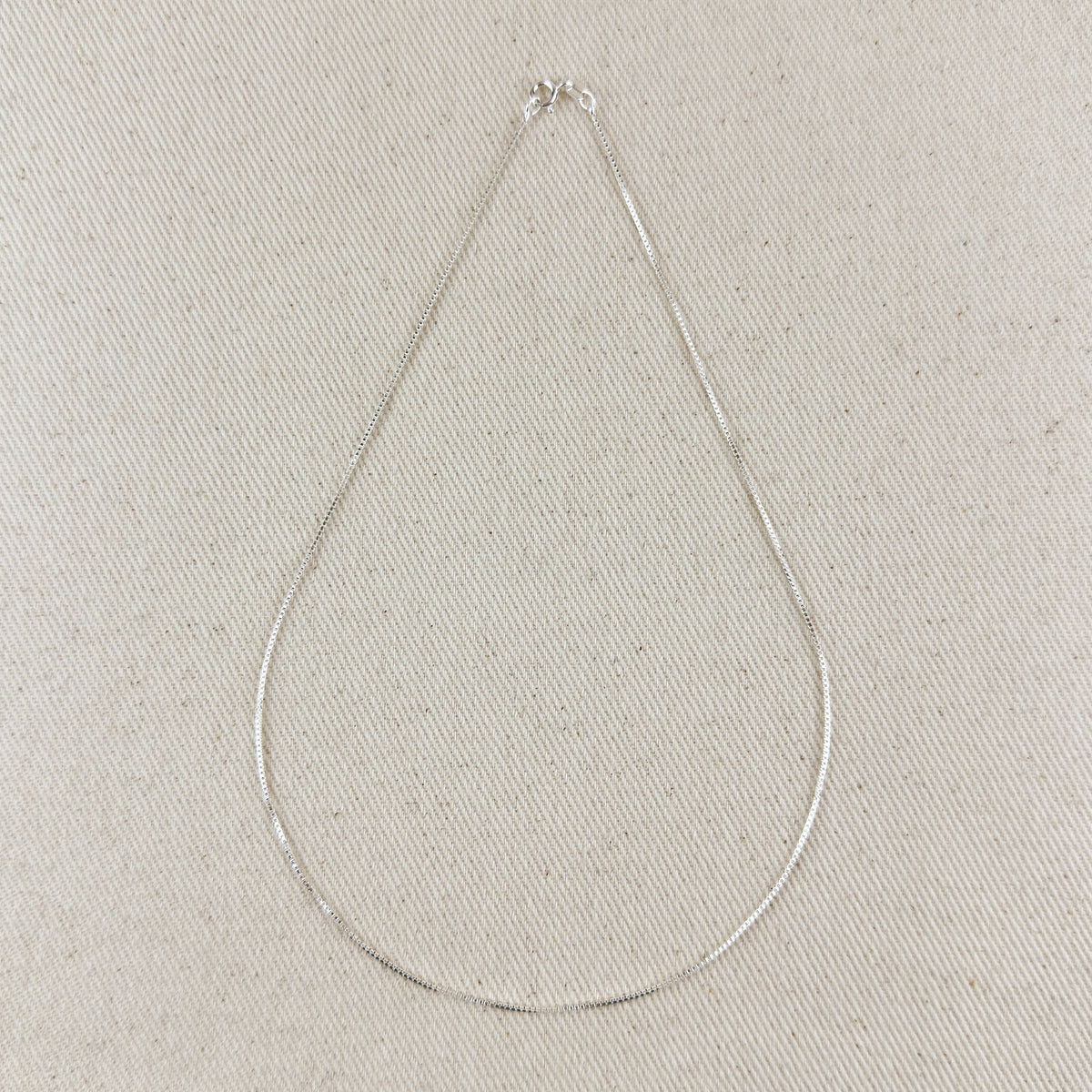 Silver necklace on a light gray textured background