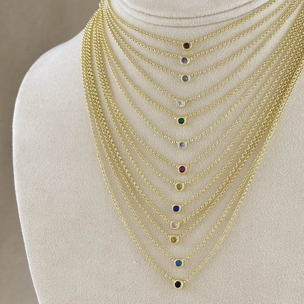 Set of gold necklaces with colored stones on a mannequin bust.