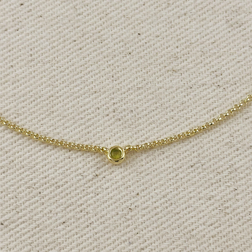 Close-up of 18K gold filled dainty necklace featuring a bezel setting, showcasing a cubic zirconia birthstone.