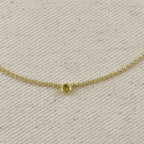 Close-up of 18K gold filled dainty necklace featuring a bezel setting, showcasing a cubic zirconia birthstone.