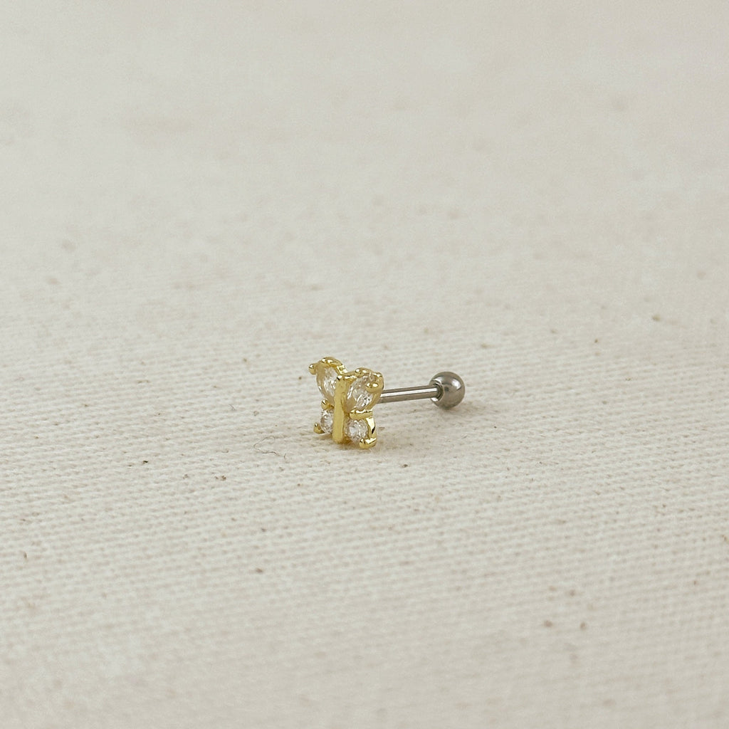 Gold and silver earring on a beige fabric background