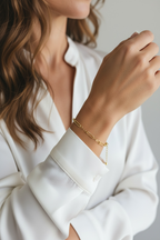 Close-up of a person wearing a gold bracelet on a plain background